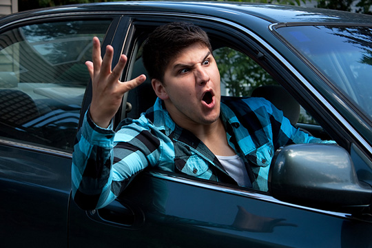 illustrates road rage with man waving arm out of car window.